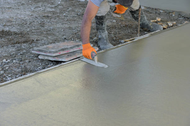 Using trowel worker plasters wet concrete cement floor after it has been poured